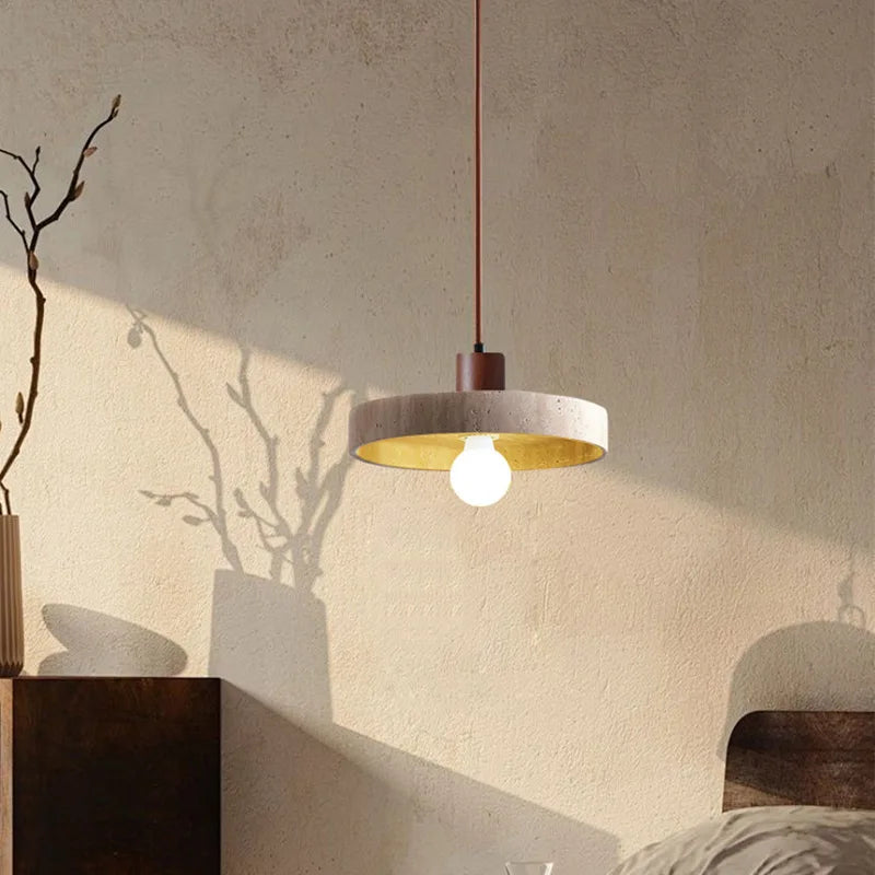 Suspension en forme de disque en pierre et bois baignée par une lumière naturelle rase dans un intérieur au design épuré.