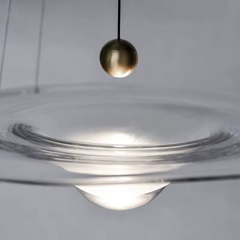 Gros plan sur une suspension disque en verre avec cœur goutte lumineux et détail sphérique doré