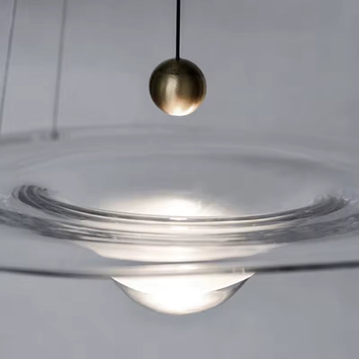 Gros plan sur une suspension disque en verre avec cœur goutte lumineux et détail sphérique doré