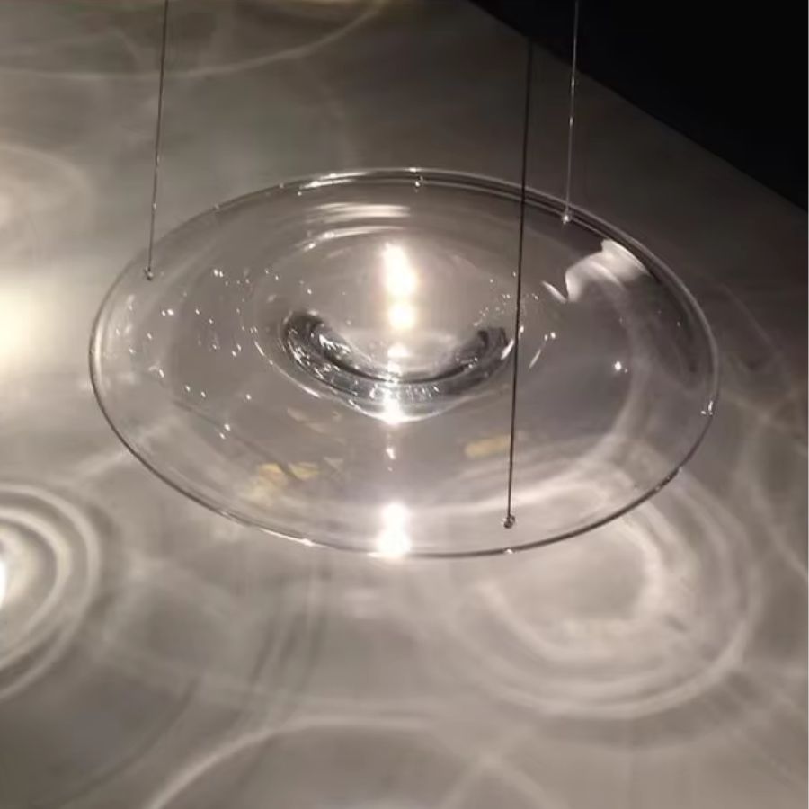 Suspension disque en verre transparent projetant des reflets lumineux, au style contemporain et aérien