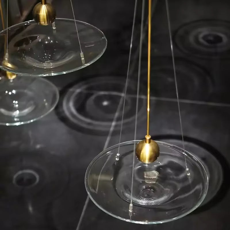 Suspensions disque en verre transparent avec détails dorés, au style design raffiné et aux reflets graphiques