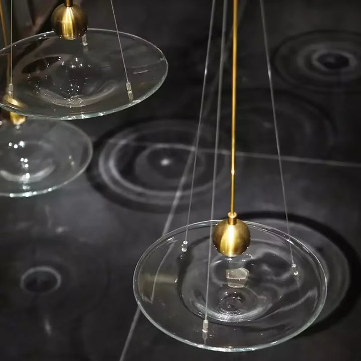 Suspensions disque en verre transparent avec détails dorés, au style design raffiné et aux reflets graphiques
