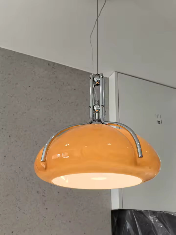 Vue rapprochée d'une suspension au dôme orange brillant et de sa structure chromée, dans un esprit Space Age inspiré des années 70