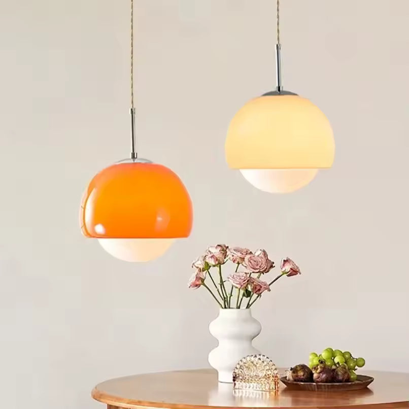 Deux suspensions rétro à dôme orange et beige avec globe opalin, installées au-dessus d’une table