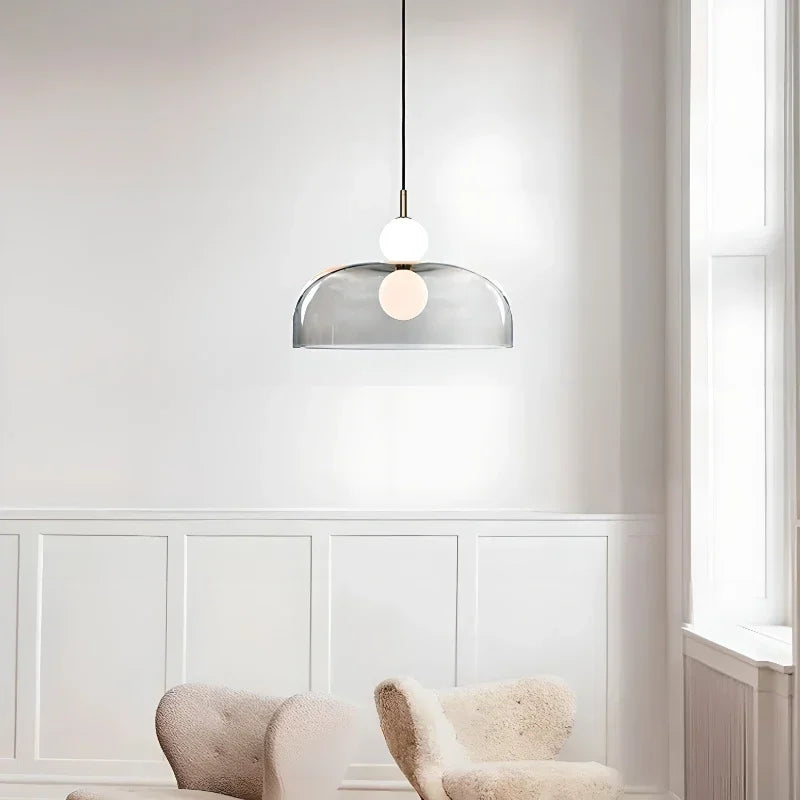 Suspension design à dôme transparent fumé et globes opalins installée dans un salon moderne et lumineux.