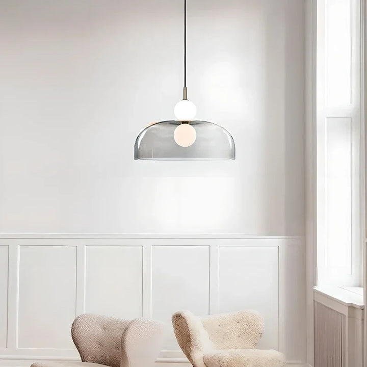 Suspension design à dôme transparent fumé et globes opalins installée dans un salon moderne et lumineux.