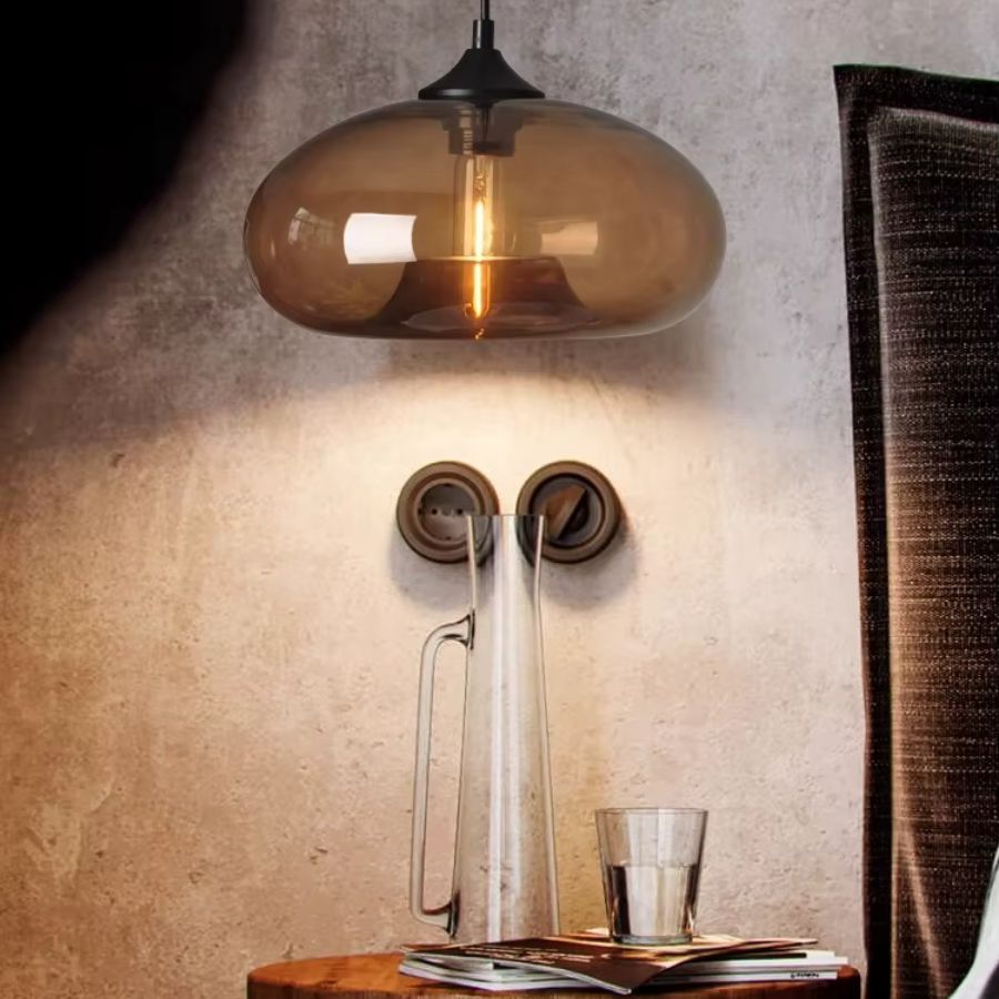 Dans une ambiance feutrée, cette suspension dôme en verre café combine inspiration vintage et élégance contemporaine