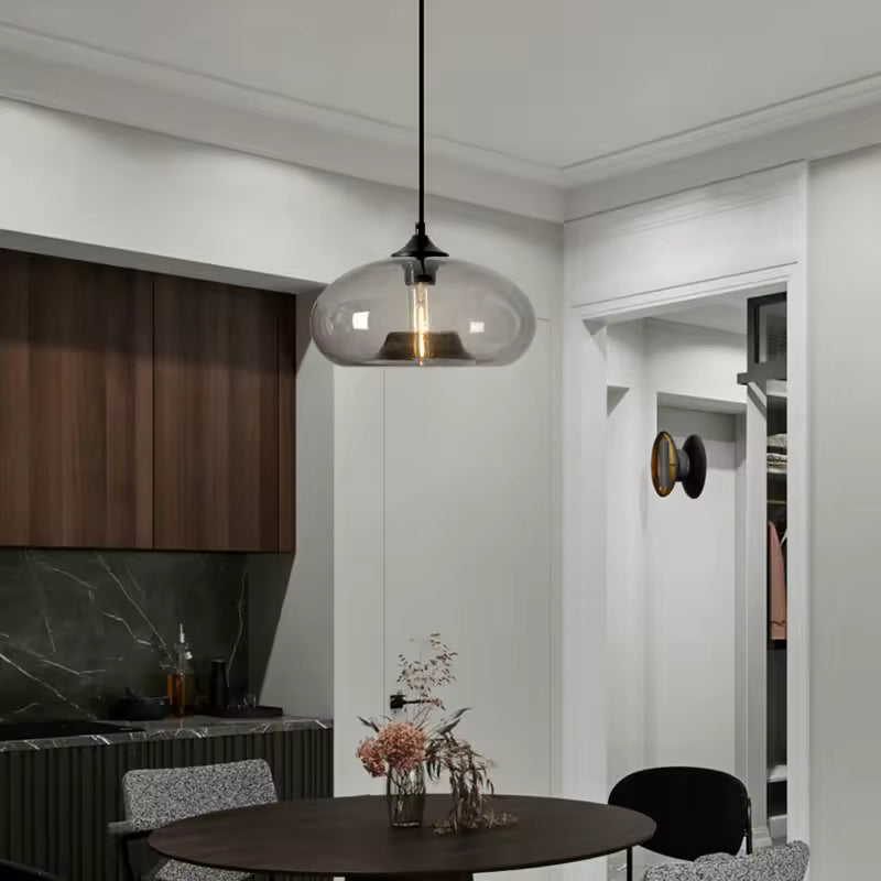 Installée au-dessus de la table, cette suspension dôme en verre fumé souligne un intérieur moderne aux accents rétro