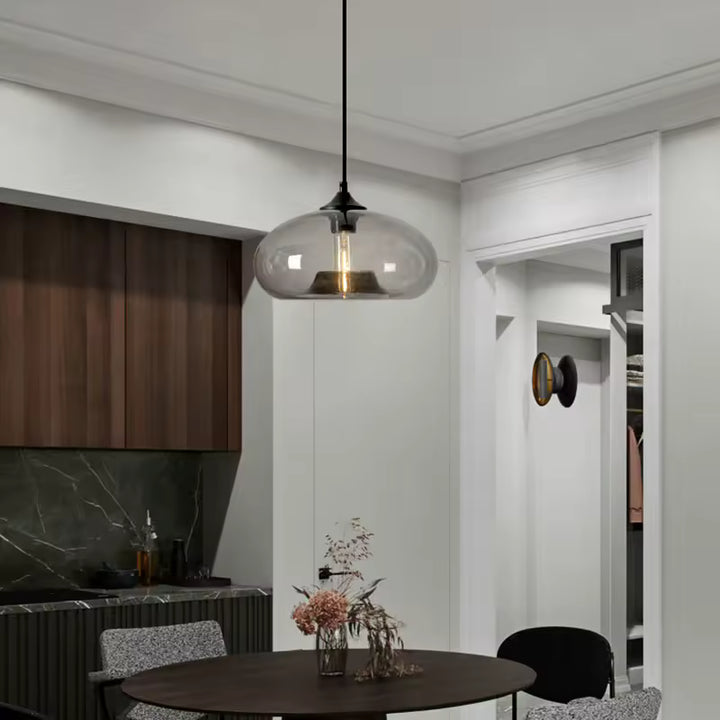 Installée au-dessus de la table, cette suspension dôme en verre fumé souligne un intérieur moderne aux accents rétro