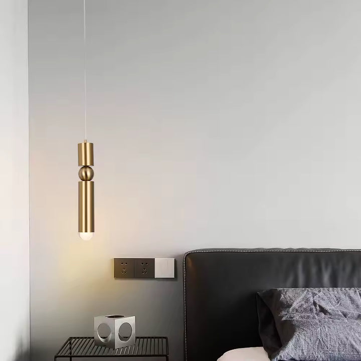 Suspension dorée allongée à sphère centrale, installée en chevet dans une chambre contemporaine et élégante