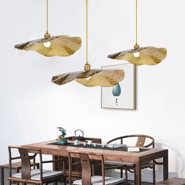 Ensemble de trois suspensions dorées martelées, parfait pour illuminer une table à manger élégante.