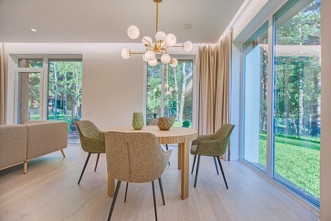 Suspension dorée design avec abat-jour blancs au-dessus d'une table ronde en bois dans une salle à manger moderne.