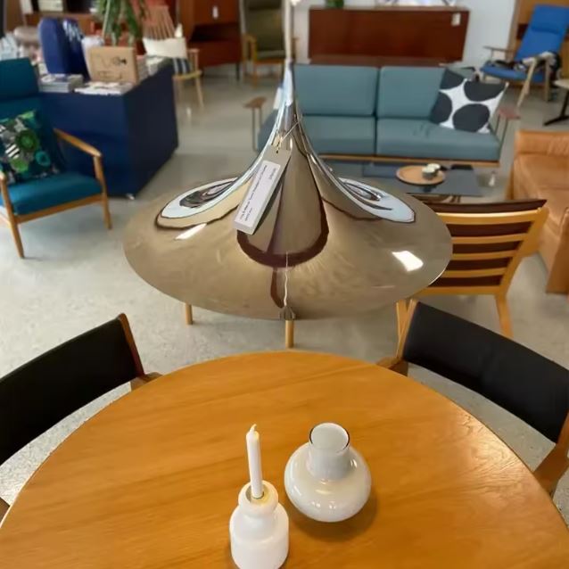 Suspension dorée brillante au-dessus d’une table ronde, dans un esprit mid-century, design italien et moderniste.