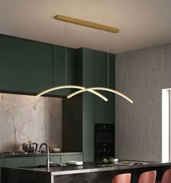 Suspension double arc LED dorée illuminant une cuisine moderne avec un îlot en marbre et des meubles verts élégants.