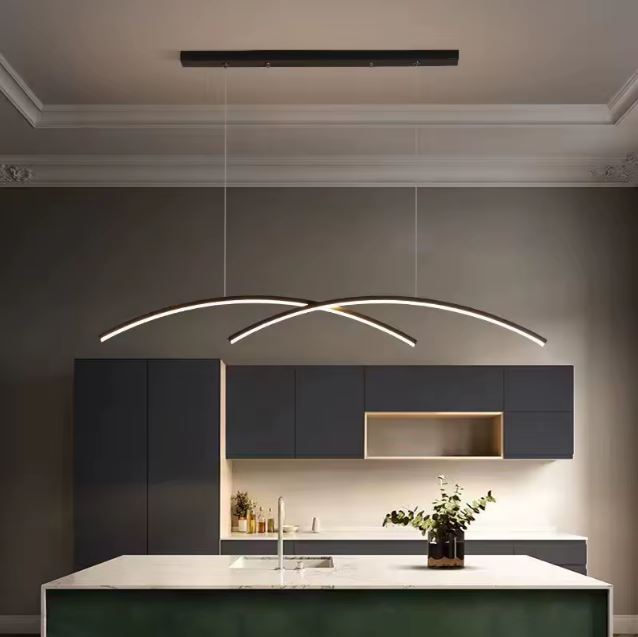 Suspension double arc LED design éclairant une cuisine moderne avec un îlot central et des meubles noirs élégants.