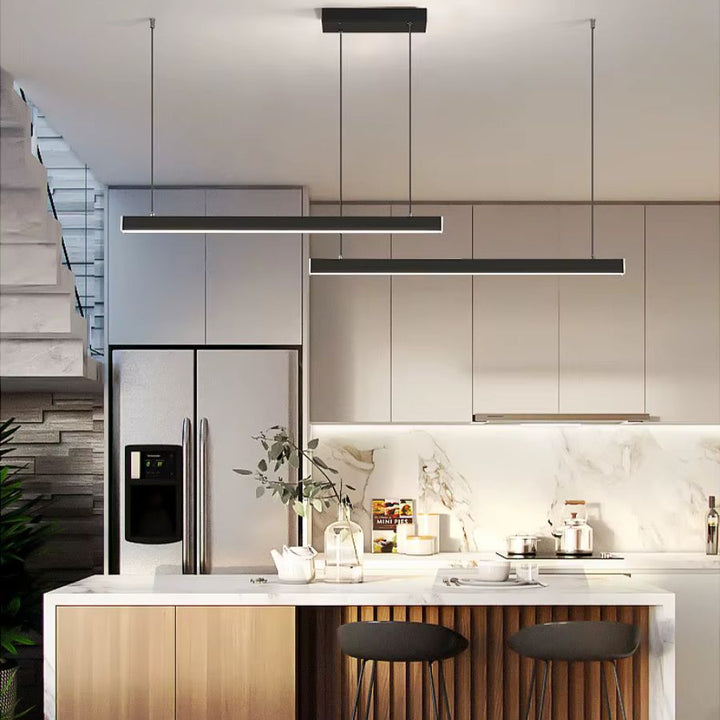 Lignes épurées et double barre LED noire structurent cette suspension minimaliste au-dessus d’un îlot de cuisine