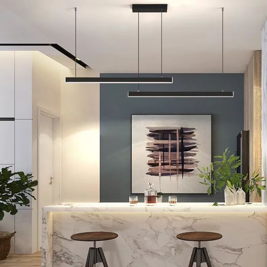 Au-dessus d’un îlot central, cette suspension noire à double barre LED adopte un design graphique et contemporain