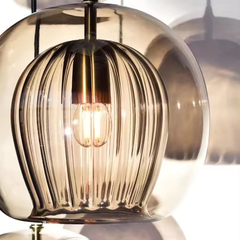 Détail sculptural d’une suspension double verre ambré avec cœur strié et reliefs verticaux autour de la lumière