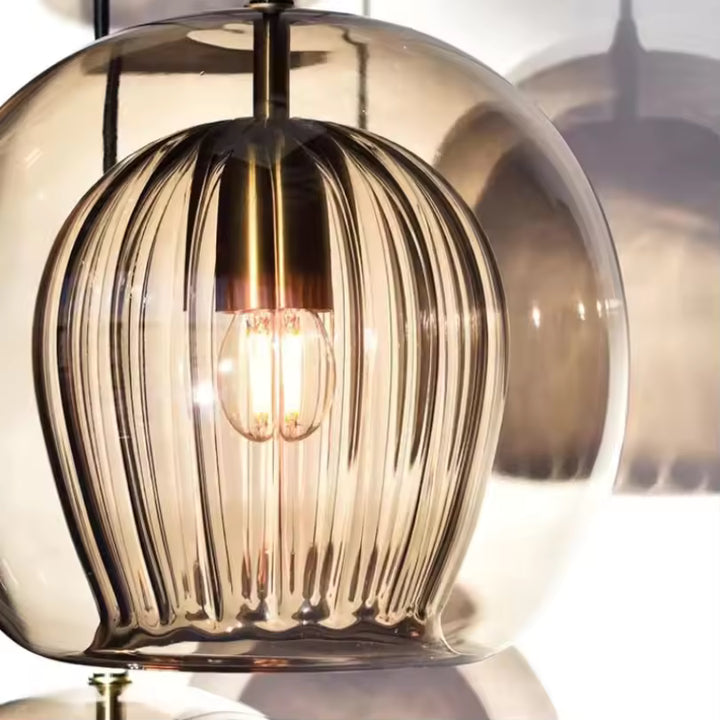 Détail sculptural d’une suspension double verre ambré avec cœur strié et reliefs verticaux autour de la lumière