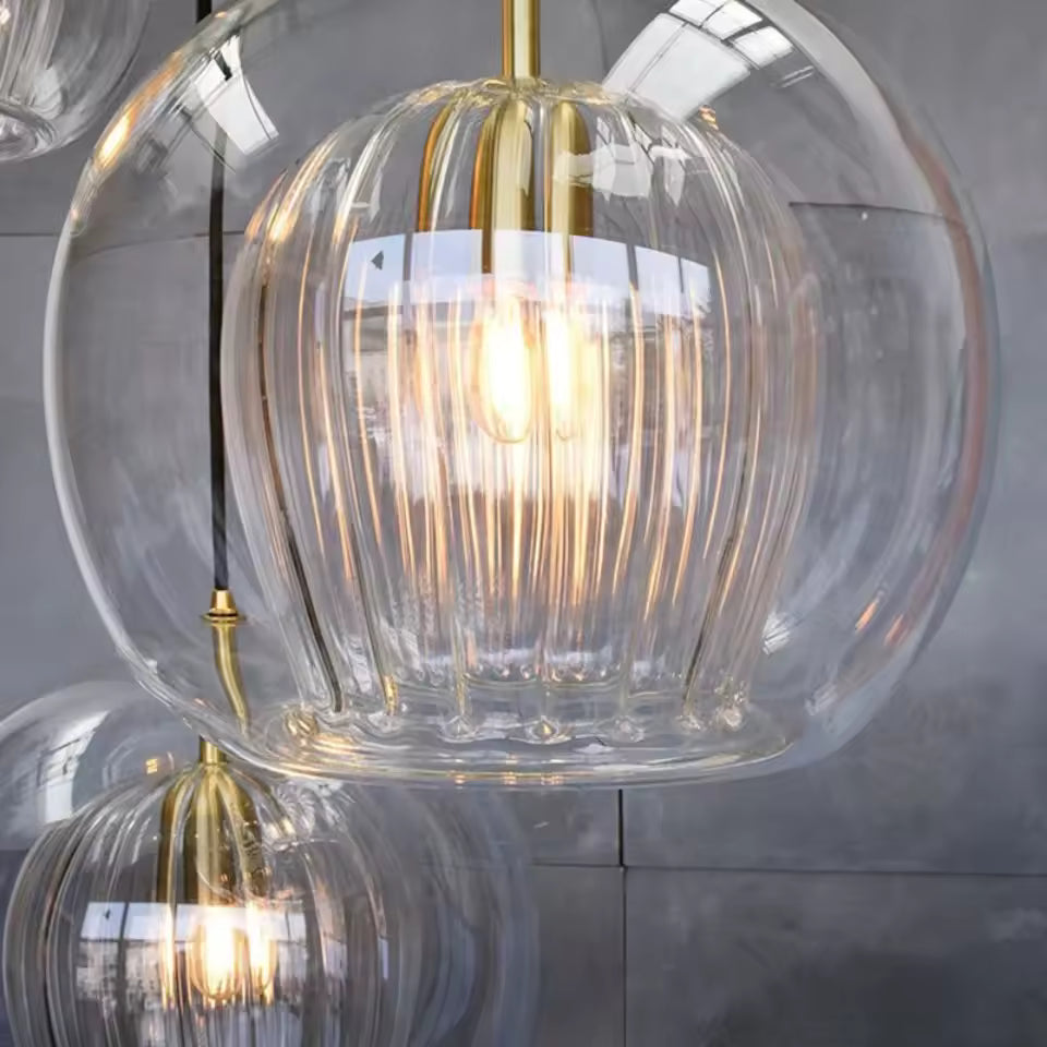 Gros plan sur une suspension double verre transparent à cœur strié et finitions dorées au style raffiné