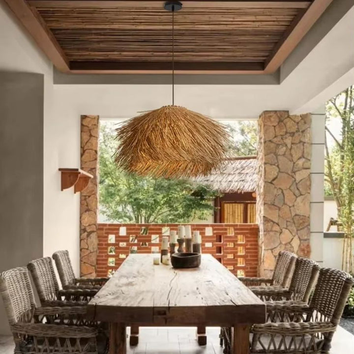 Suspension en paille en forme de chapeau au-dessus d’une grande table, dans une ambiance exotique et naturelle