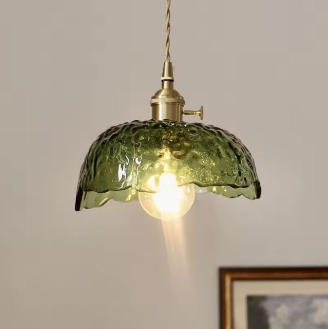 Suspension en verre vert au style rétro avec douille en laiton doré, diffusant une lumière douce et chaleureuse.