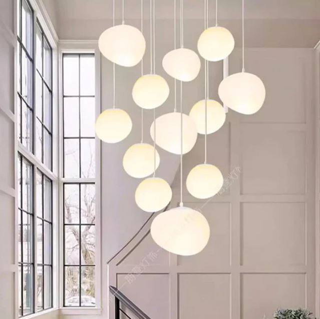 Suspension escalier boule au style épuré, idéale pour un intérieur lumineux avec grande hauteur sous plafond et fenêtres verticales.