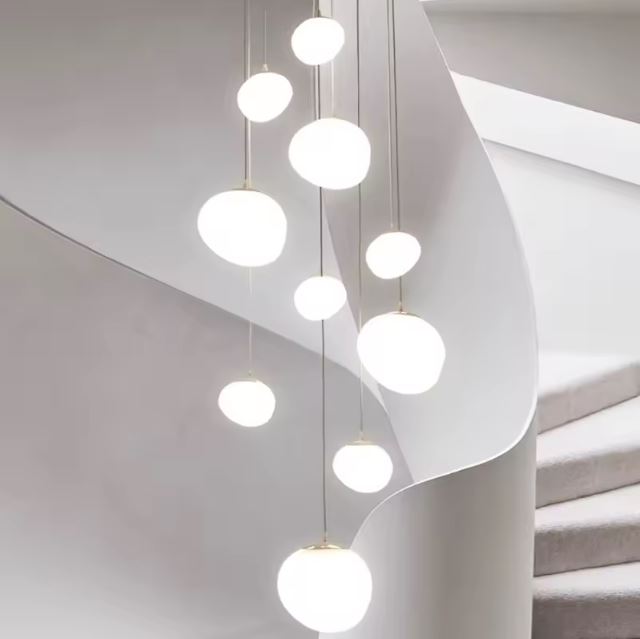Suspension escalier boule blanche sublimant un escalier minimaliste aux lignes épurées et modernes, idéale pour une déco lumineuse.