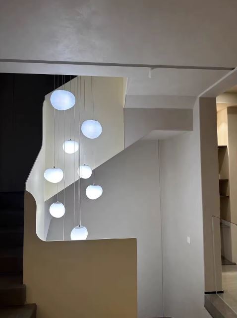 Suspension escalier boule au design contemporain installée dans une cage d’escalier claire et minimaliste.