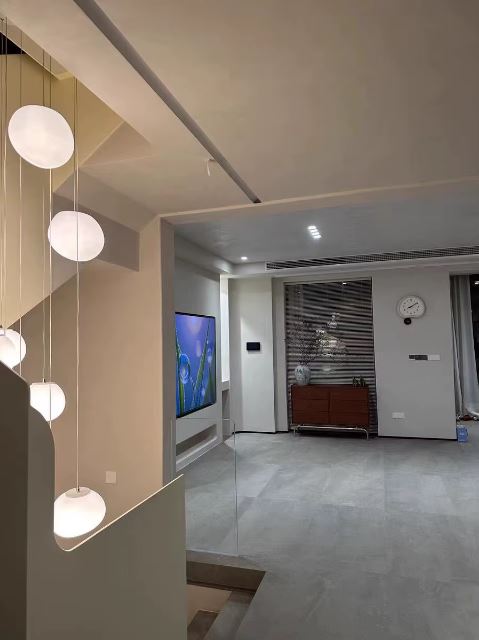 Suspension escalier boule installée dans un intérieur moderne avec escalier tournant et lumière chaude.