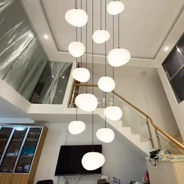 Suspension escalier boule installée dans un salon à double hauteur, idéale pour éclairer un espace contemporain avec élégance.