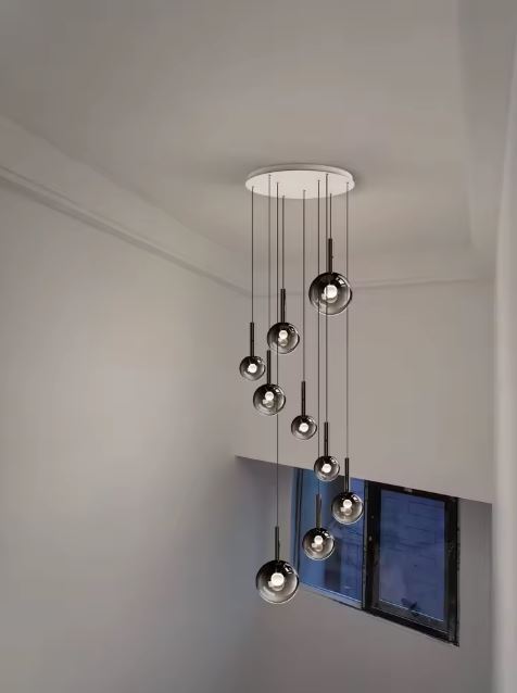 Suspension d’escalier pour plafond haut, globes en verre fumé noir, style moderne sobre et raffiné.