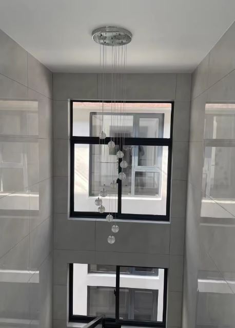 Suspension verticale de globes en verre pour cage d’escalier, éclairage design élégant et parfaitement adapté aux grandes hauteurs.
