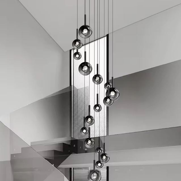 Suspension XXL en cascade pour escalier, globes en verre fumé noir, style moderne graphique.