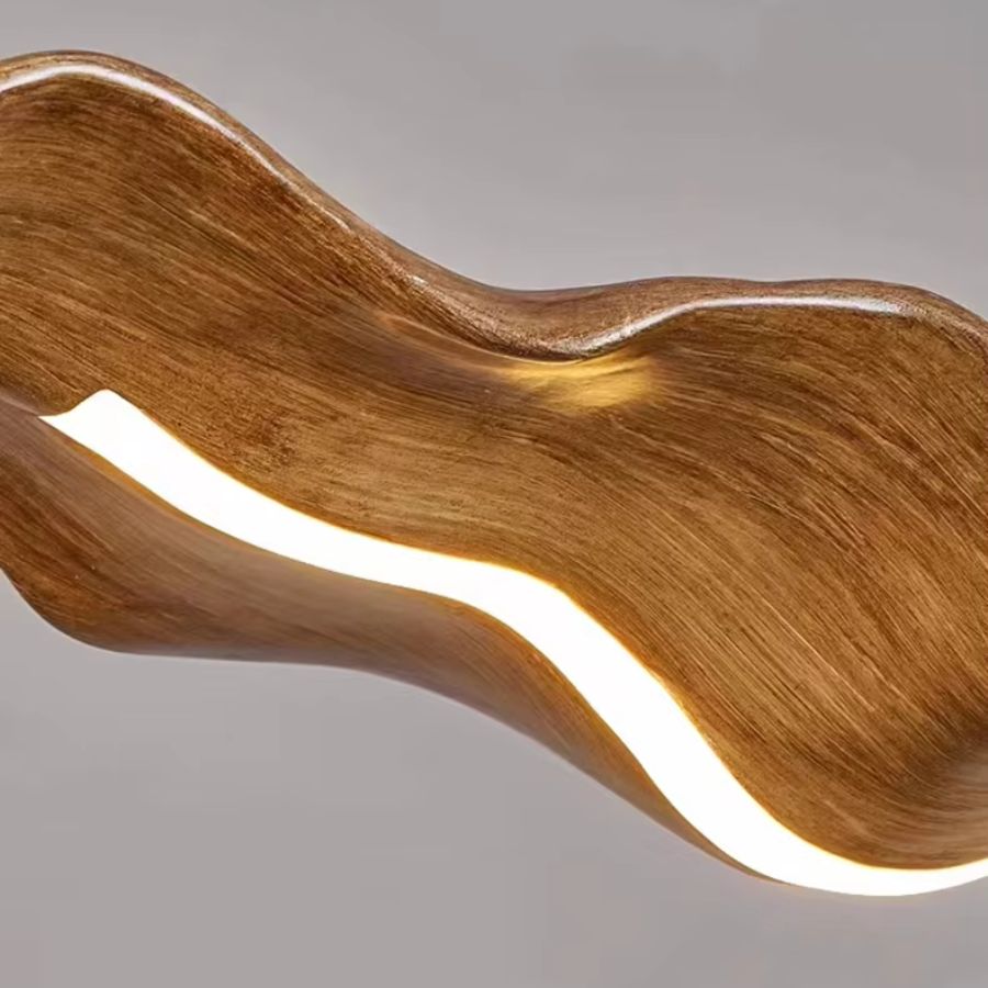 Gros plan sur une suspension feuille effet bois aux courbes fluides, avec ruban LED intégré et design organique
