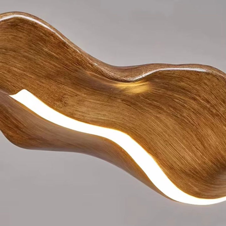 Gros plan sur une suspension feuille effet bois aux courbes fluides, avec ruban LED intégré et design organique