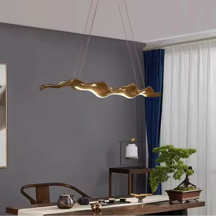 Suspension feuille ondulée marron au style sculptural et organique, au-dessus d’une table contemporaine