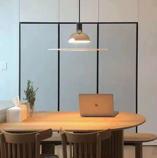 Suspension fine chromée au-dessus d’un bureau en bois, parfaite pour un espace de travail au style scandinave.