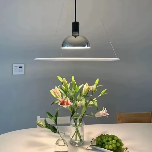 Suspension fine chromée au-dessus d’une table fleurie, idéale pour une salle à manger élégante et lumineuse.