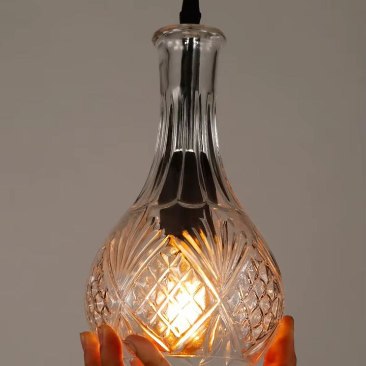 Gros plan sur une suspension flacon en verre transparent taillé, aux motifs rétro et à la lumière chaude décorative