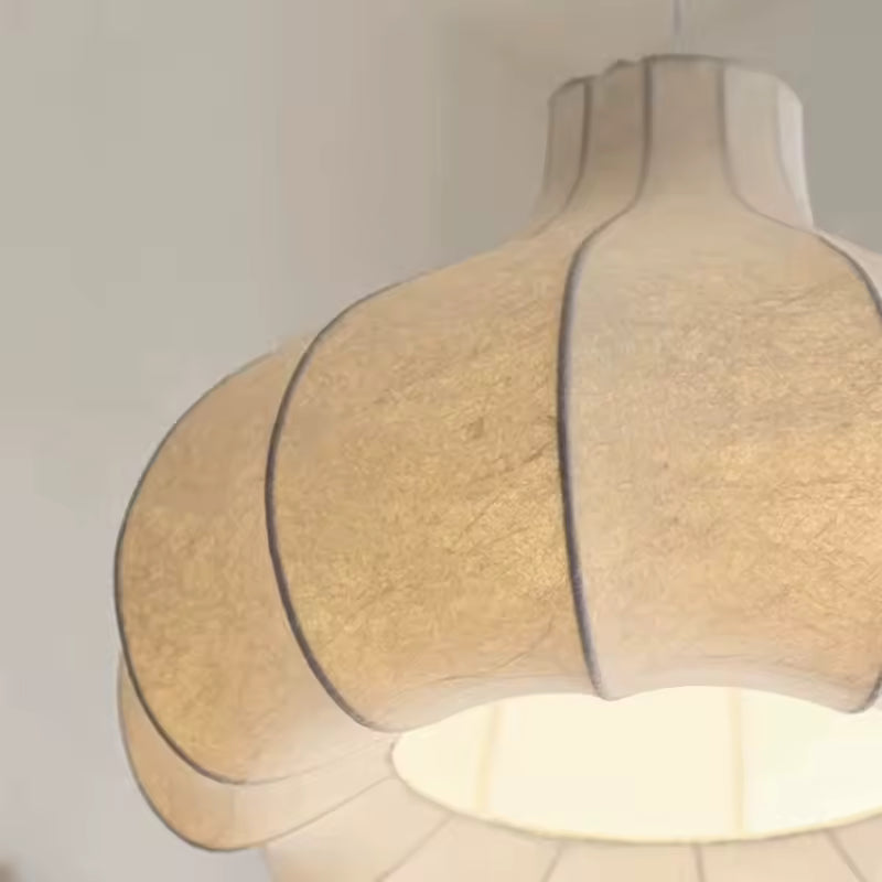 Détail d'une suspension en soie blanche au design japonais, avec abat-jour sculptural aux pétales courbés et lumière douce.