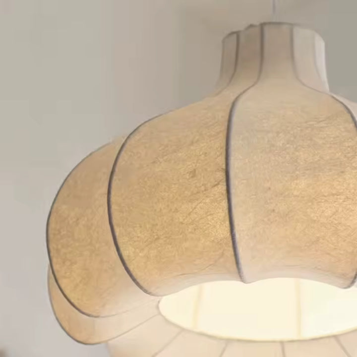 Détail d'une suspension en soie blanche au design japonais, avec abat-jour sculptural aux pétales courbés et lumière douce.