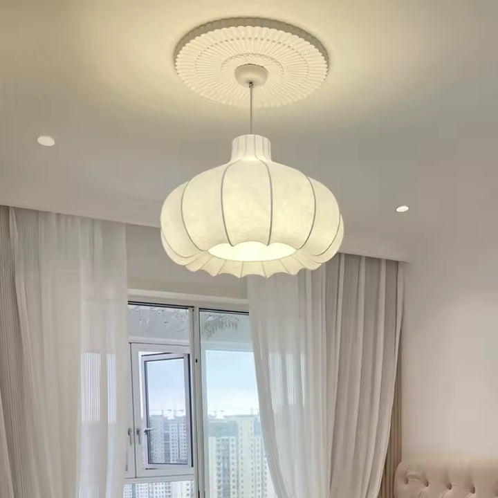 Luminaire floral en soie blanche au design japonais, suspendu dans une chambre lumineuse aux rideaux clairs.
