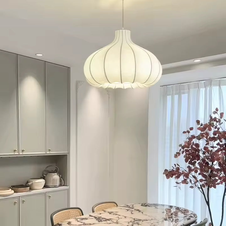 Au-dessus d'une table en marbre, suspension florale en soie blanche au style Japandi, éclairant une salle à manger épurée.