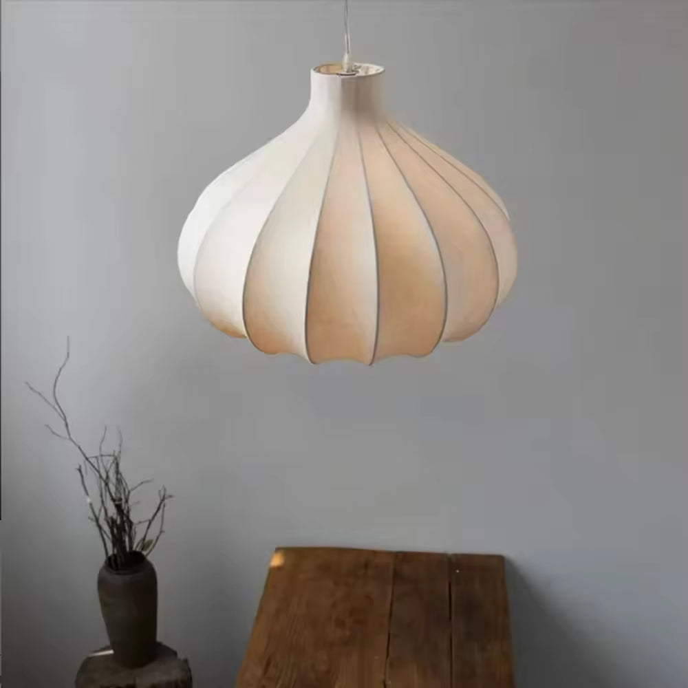 Au-dessus d'une table en bois, suspension japonaise en soie blanche aux courbes florales, dans une ambiance Wabi-Sabi épurée.