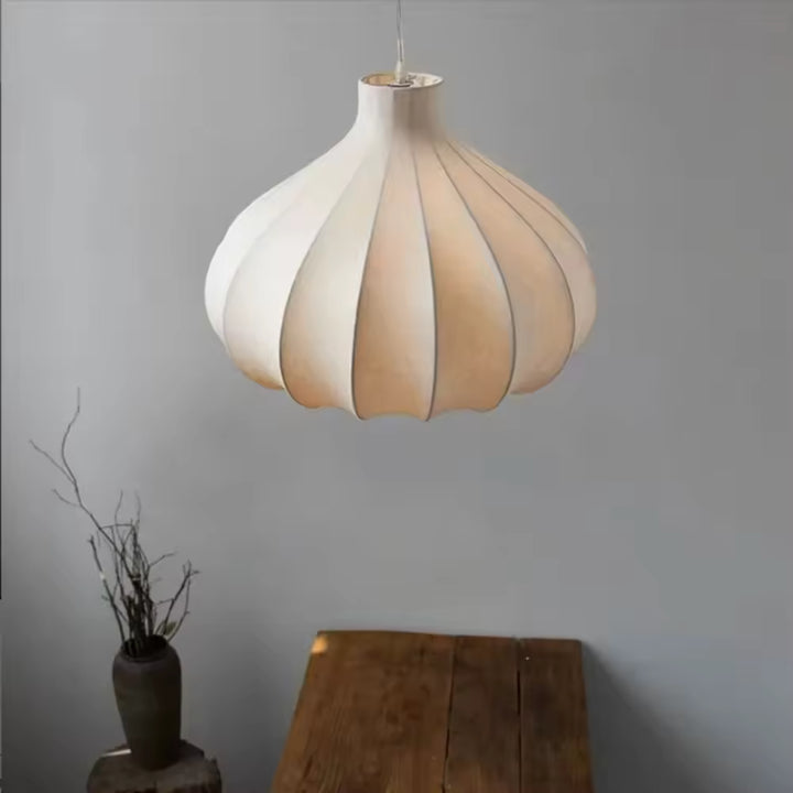 Au-dessus d'une table en bois, suspension japonaise en soie blanche aux courbes florales, dans une ambiance Wabi-Sabi épurée.