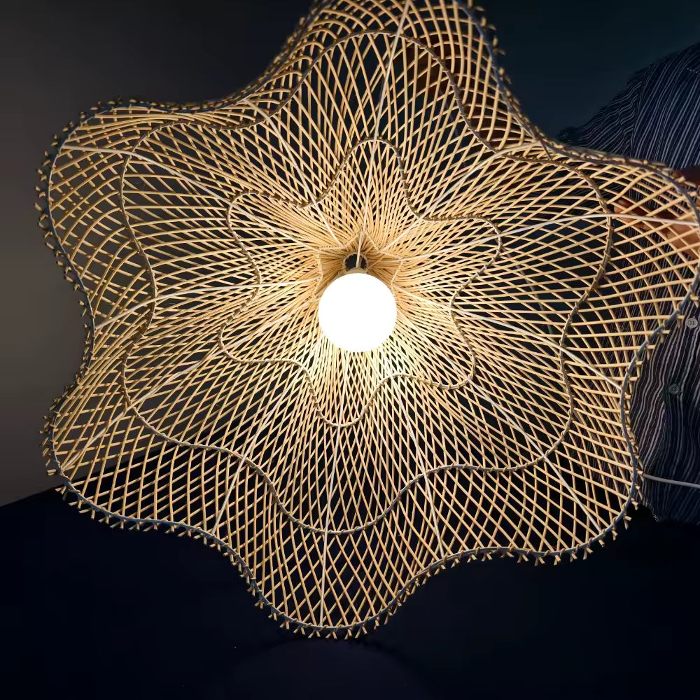 Éclairée par le centre, la corolle en rotin tressé révèle une forme de lotus au style organique et sculptural