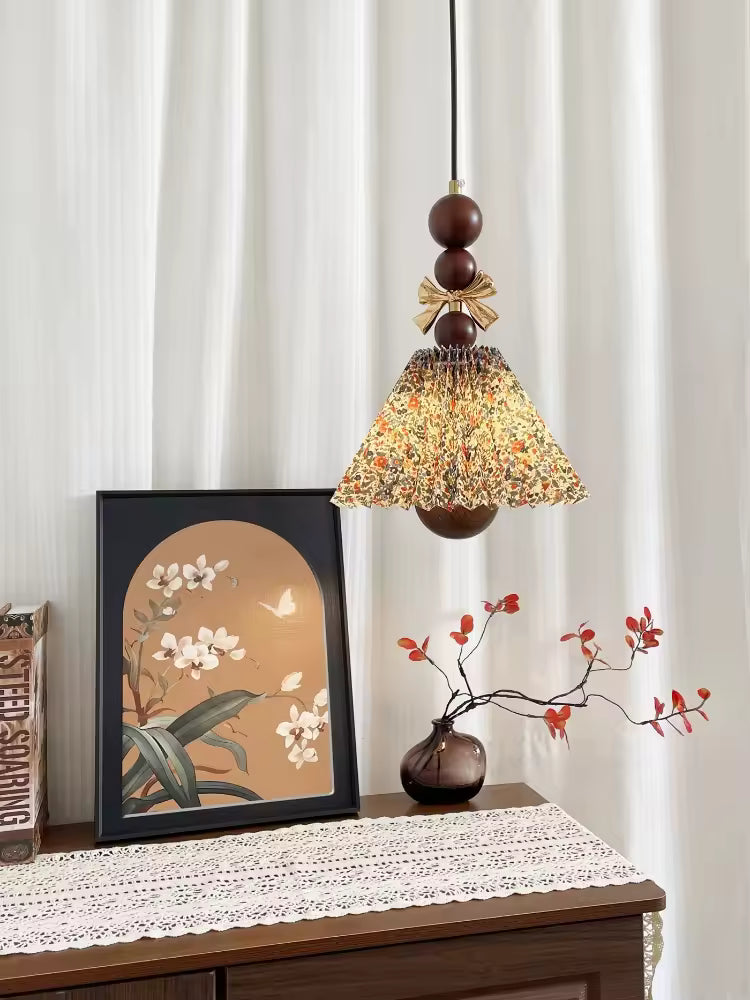 Dans un intérieur chaleureux, cette suspension florale en tissu plissé et bois affiche un style vintage délicat