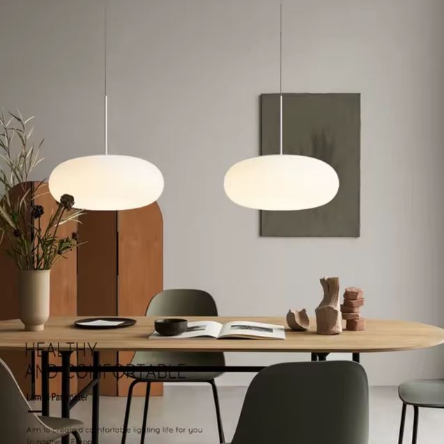 Deux Suspensions Galet Flottant en Verre Opalin au-dessus d'une table en bois dans un intérieur scandinave contemporain