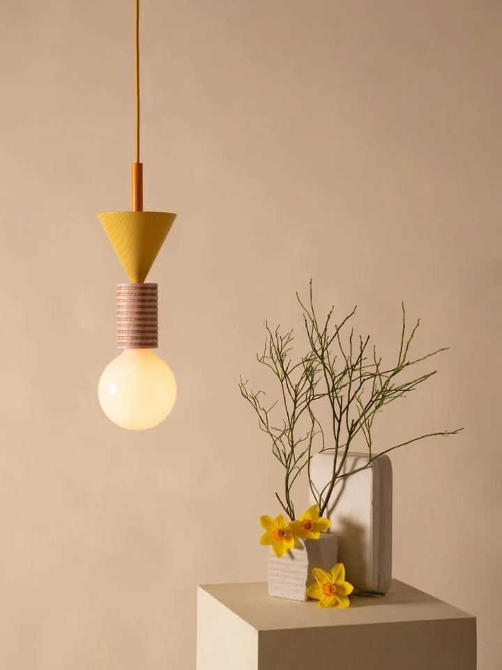 Lampe suspendue totem en bois avec éléments géométriques jaune et rouge dans un décor épuré.